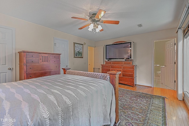 bedroom featuring baseboards, visible vents, light wood finished floors, ceiling fan, and a textured ceiling