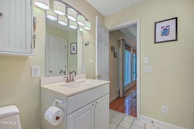 half bath featuring vanity, toilet, baseboards, and tile patterned flooring