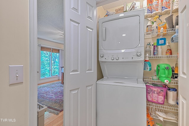 washroom featuring laundry area, stacked washer and clothes dryer, a textured ceiling, and wood finished floors