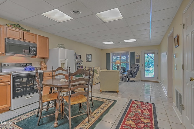 dining area with light tile patterned floors, visible vents, baseboards, and a drop ceiling