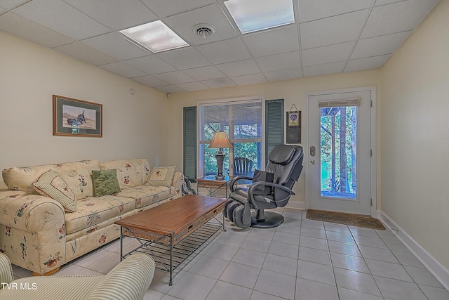 living room featuring light tile patterned floors, a paneled ceiling, visible vents, and baseboards