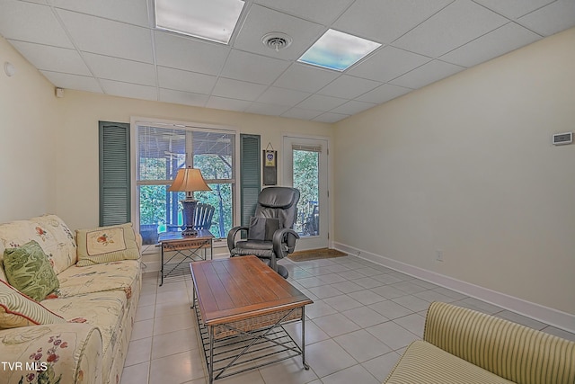 living room with visible vents, a paneled ceiling, baseboards, and light tile patterned flooring