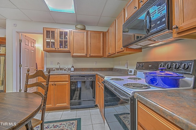 kitchen featuring black appliances, light tile patterned floors, a drop ceiling, and a sink