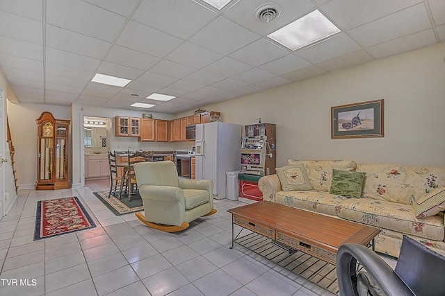 living room with light tile patterned floors, visible vents, a paneled ceiling, and baseboards