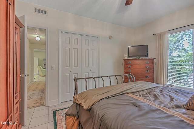 bedroom with light tile patterned flooring, visible vents, a closet, and ceiling fan