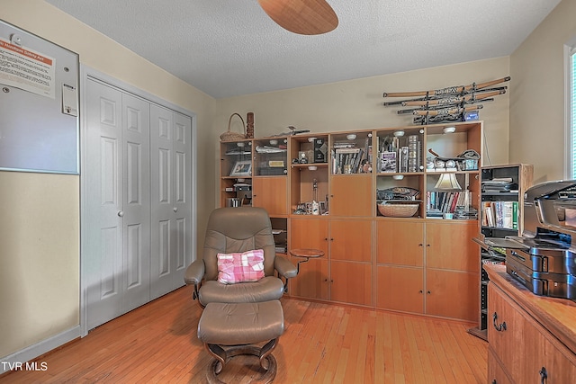 living area with light wood-type flooring and a textured ceiling