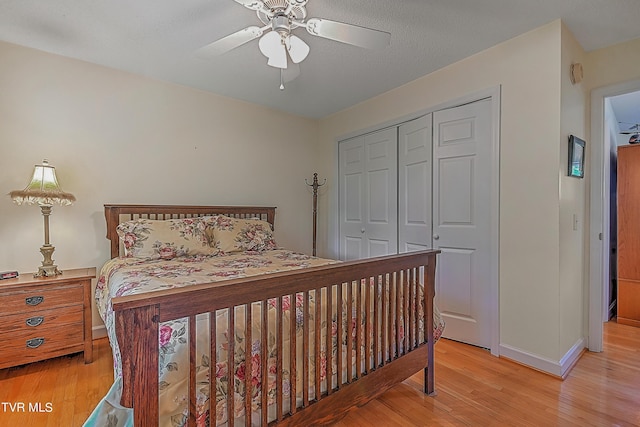 bedroom with light wood-style flooring, a ceiling fan, a closet, and baseboards