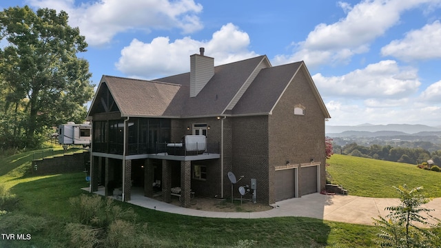 rear view of property featuring a yard, a garage, a mountain view, and a balcony