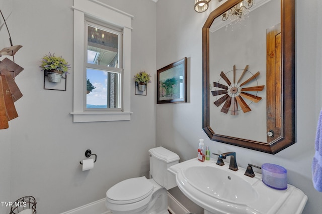 half bathroom with toilet, baseboards, and a sink