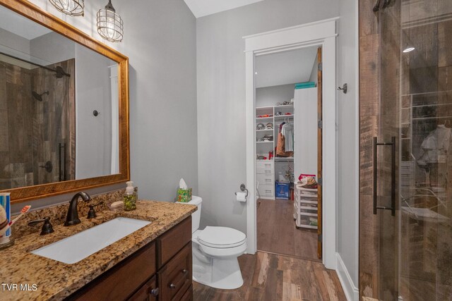 bathroom featuring a shower with shower door, toilet, hardwood / wood-style floors, and vanity