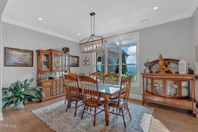 dining room with crown molding, a notable chandelier, and hardwood / wood-style floors