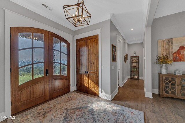 foyer featuring crown molding, hardwood / wood-style floors, a chandelier, and french doors