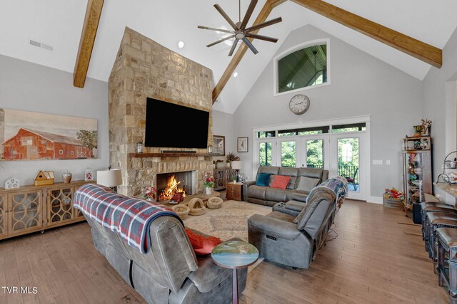 living room with a fireplace, beam ceiling, high vaulted ceiling, ceiling fan, and light wood-type flooring