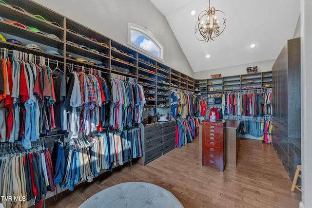 walk in closet featuring high vaulted ceiling, wood finished floors, and a chandelier