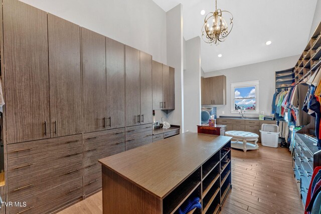 spacious closet with light hardwood / wood-style flooring and a notable chandelier