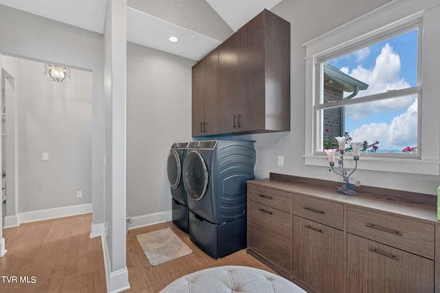 laundry room featuring light hardwood / wood-style flooring, cabinets, and washer and dryer