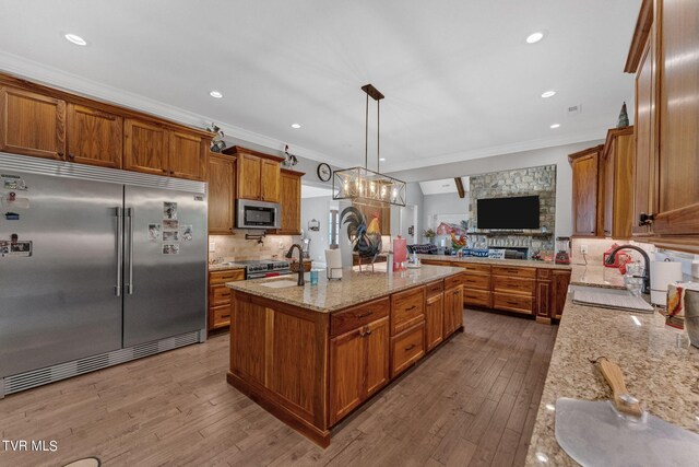 kitchen featuring dark hardwood / wood-style floors, a kitchen island with sink, hanging light fixtures, sink, and premium appliances