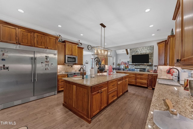 kitchen with a sink, stainless steel appliances, brown cabinets, and open floor plan