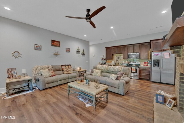 living room with light hardwood / wood-style flooring, ceiling fan, and sink