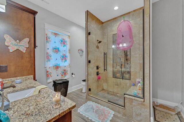 bathroom with a shower with door, vanity, toilet, and hardwood / wood-style floors