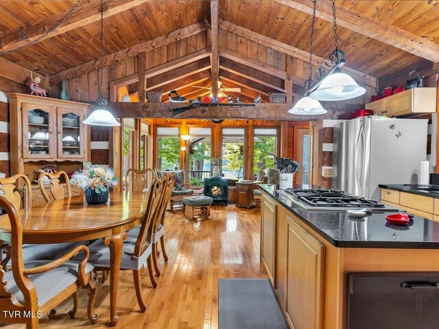 kitchen featuring french doors, light wood-type flooring, decorative light fixtures, appliances with stainless steel finishes, and vaulted ceiling with beams