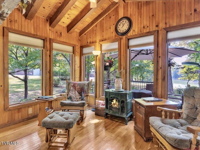 sunroom with a wood stove, lofted ceiling with beams, and wooden ceiling