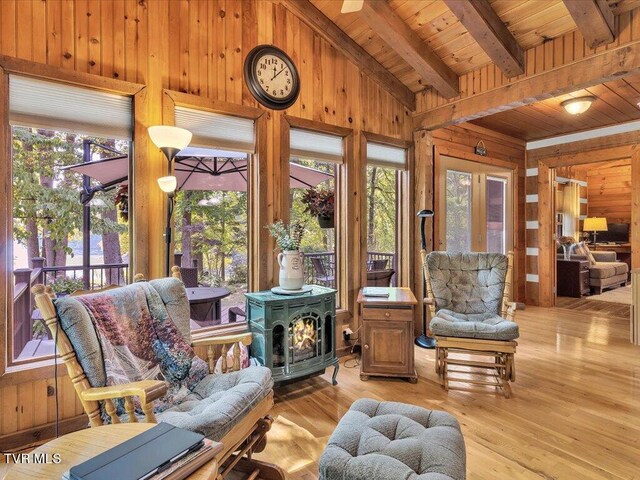 sunroom / solarium featuring wood ceiling, a wood stove, and vaulted ceiling with beams