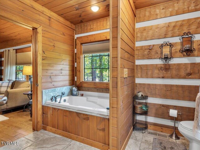 bathroom featuring a bath, toilet, wooden walls, and wooden ceiling