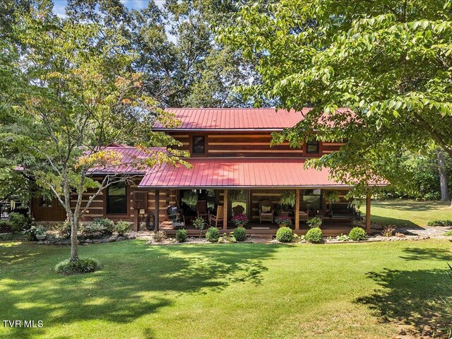 rear view of house with covered porch and a lawn