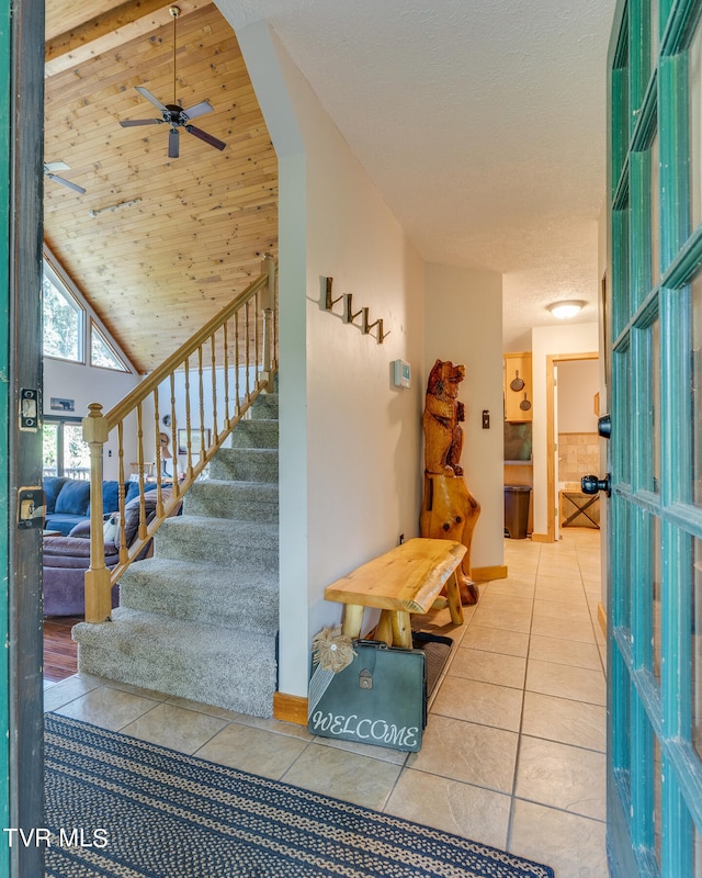 foyer with ceiling fan, high vaulted ceiling, a textured ceiling, light tile patterned flooring, and wood ceiling