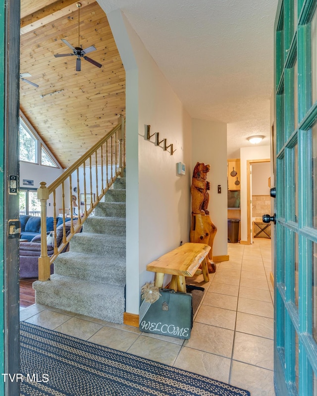 interior space featuring lofted ceiling, tile patterned flooring, wood ceiling, and a ceiling fan