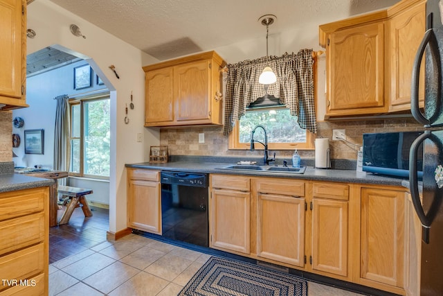 kitchen with dark countertops, black appliances, a healthy amount of sunlight, and a sink