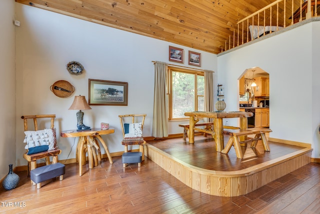 living area featuring a high ceiling, light hardwood / wood-style floors, and wooden ceiling