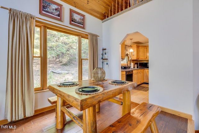 dining room with wood ceiling, baseboards, arched walkways, and light wood-style flooring