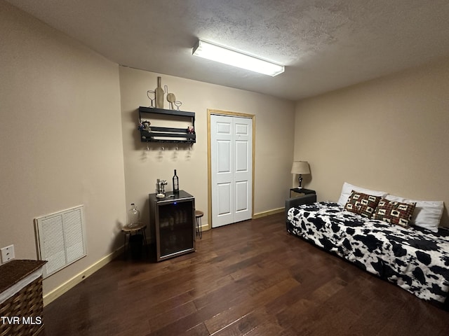 bedroom with a textured ceiling, dark hardwood / wood-style flooring, and a closet