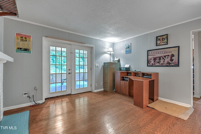 home office featuring wooden walls, ornamental molding, a textured ceiling, wood-type flooring, and french doors