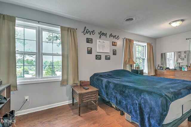 bedroom with a textured ceiling and hardwood / wood-style flooring