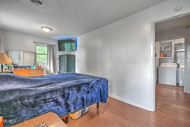 bedroom with a textured ceiling, washing machine and dryer, and hardwood / wood-style flooring