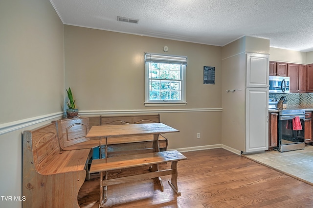 dining space featuring light wood-type flooring and a textured ceiling