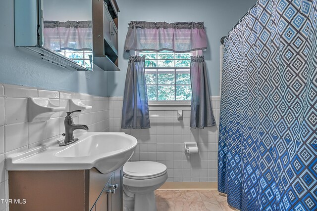 bathroom featuring tile walls, toilet, and vanity