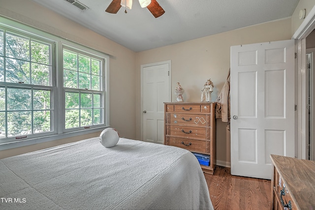 bedroom featuring dark wood-type flooring, ceiling fan, and multiple windows