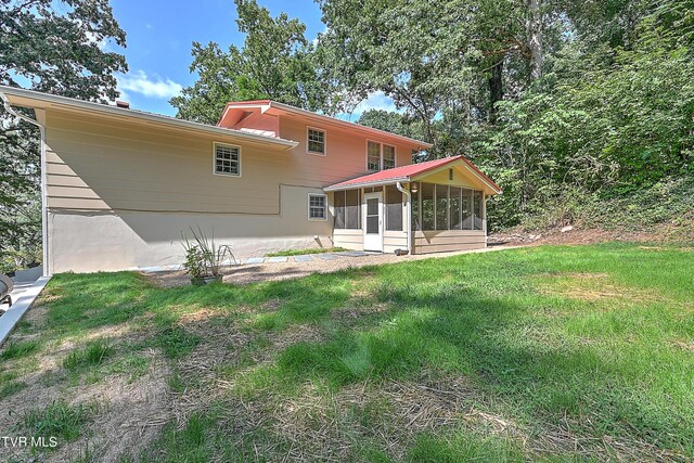 back of property with a lawn and a sunroom