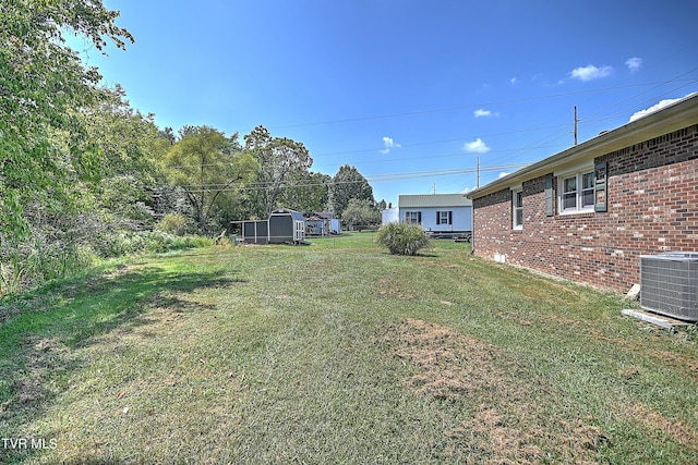 view of yard with an outbuilding, a shed, and central AC