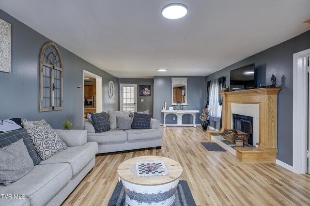 living room with light hardwood / wood-style flooring and a tiled fireplace