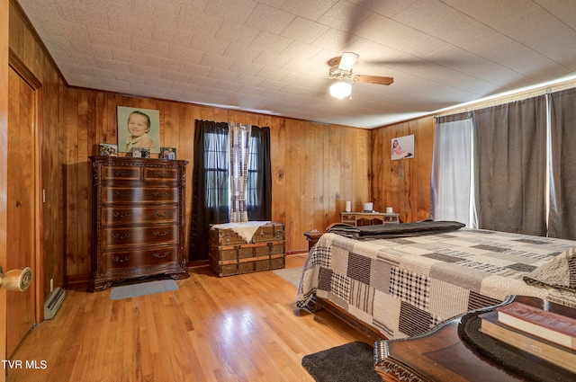 bedroom featuring wood walls, ceiling fan, and light hardwood / wood-style floors