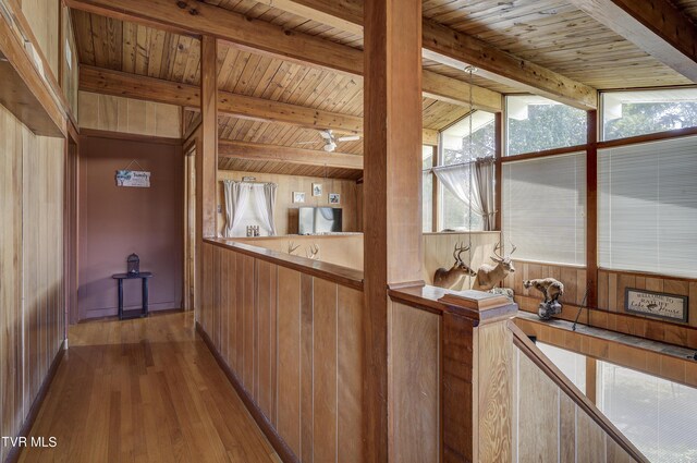 kitchen with light wood-type flooring, wood ceiling, wooden walls, and vaulted ceiling with beams