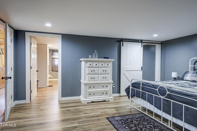 bedroom featuring light wood-type flooring and a barn door