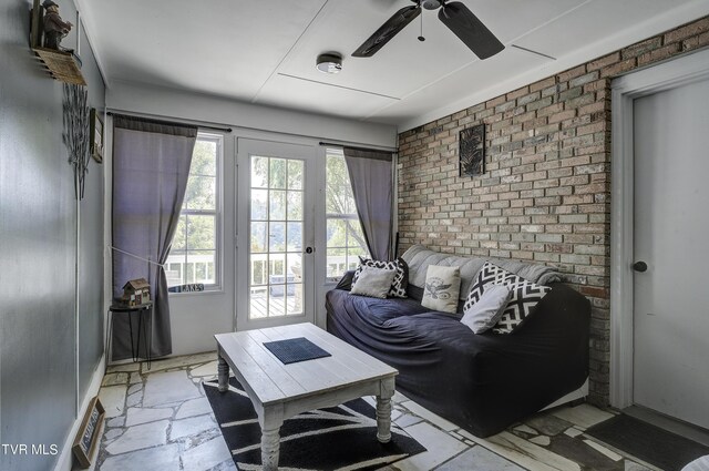 living room featuring plenty of natural light, brick wall, and ceiling fan