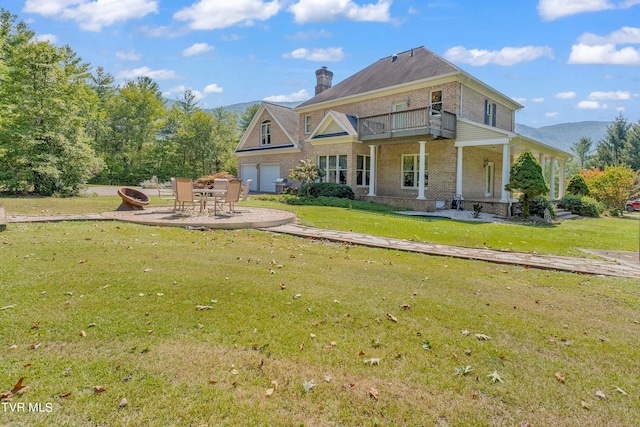 back of house with a balcony, a lawn, covered porch, and a patio