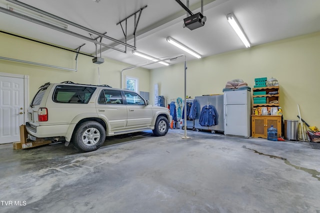 garage with a garage door opener and white fridge